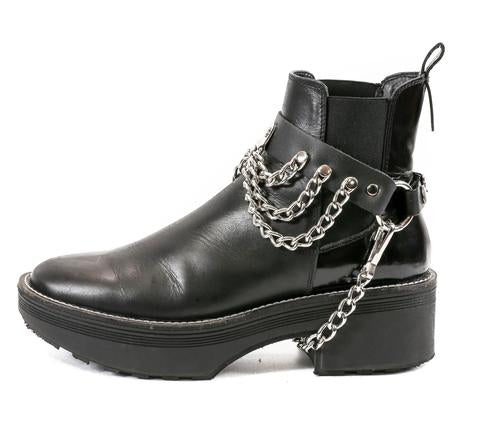 ankle boot displaying black leather boot strap with front hanging three row silver chains and hanging silver chain underneath booth